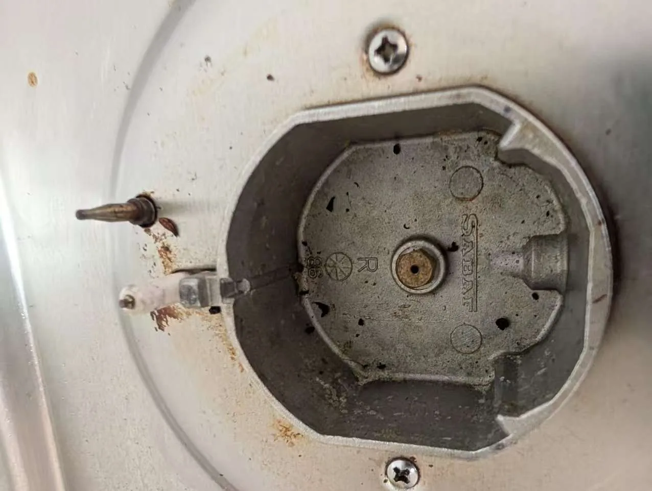 Cooktop burner base exposed for cleaning and inspection