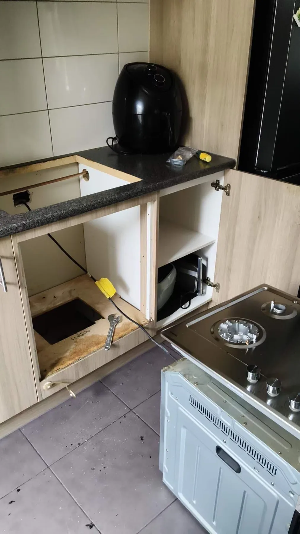 Under-bench appliance access beside kitchen cabinetry and plumbing