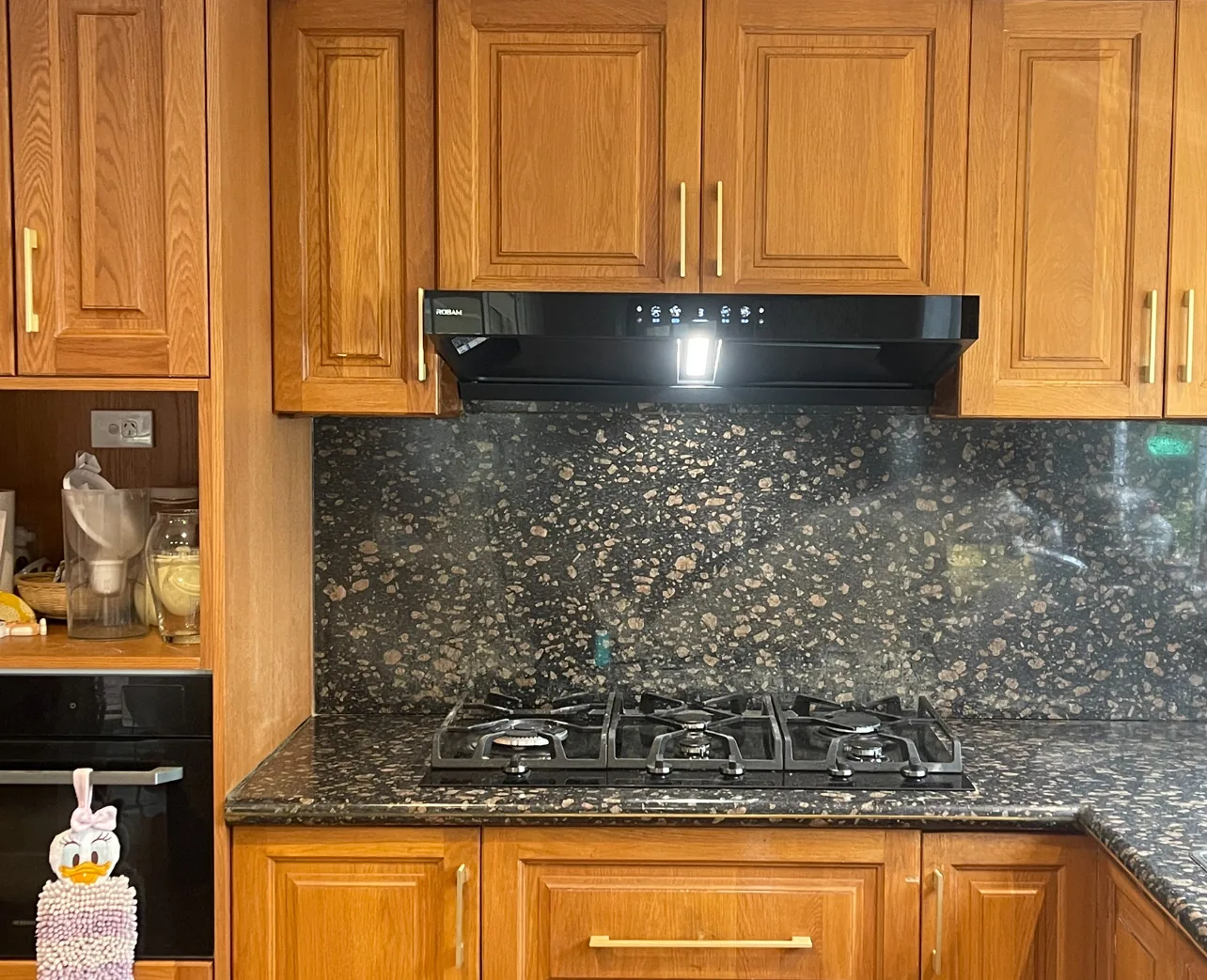Rangehood operating above a cooktop in a timber kitchen